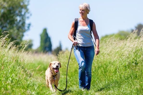 A woman hiking with her dog outside